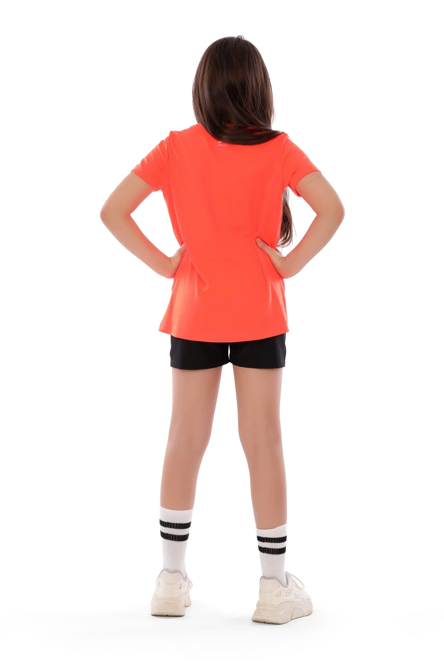 Person wearing a bright orange shirt and black shorts on a white background