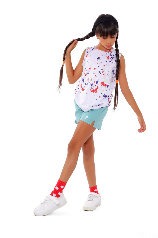 Young girl wearing a colorful sleeveless top and light blue shorts on a white background