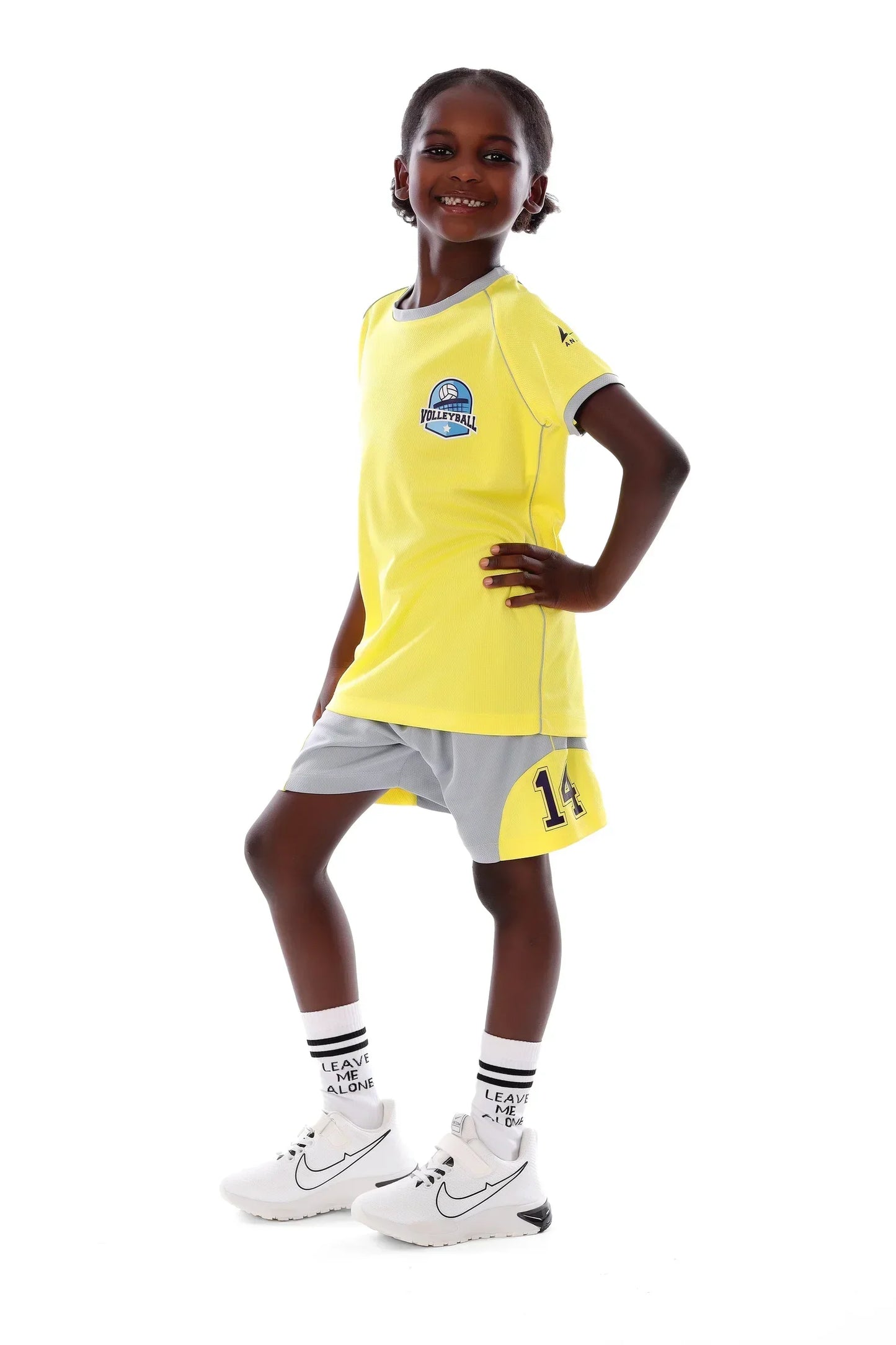 Child wearing a yellow sports jersey with gray shorts on a white background