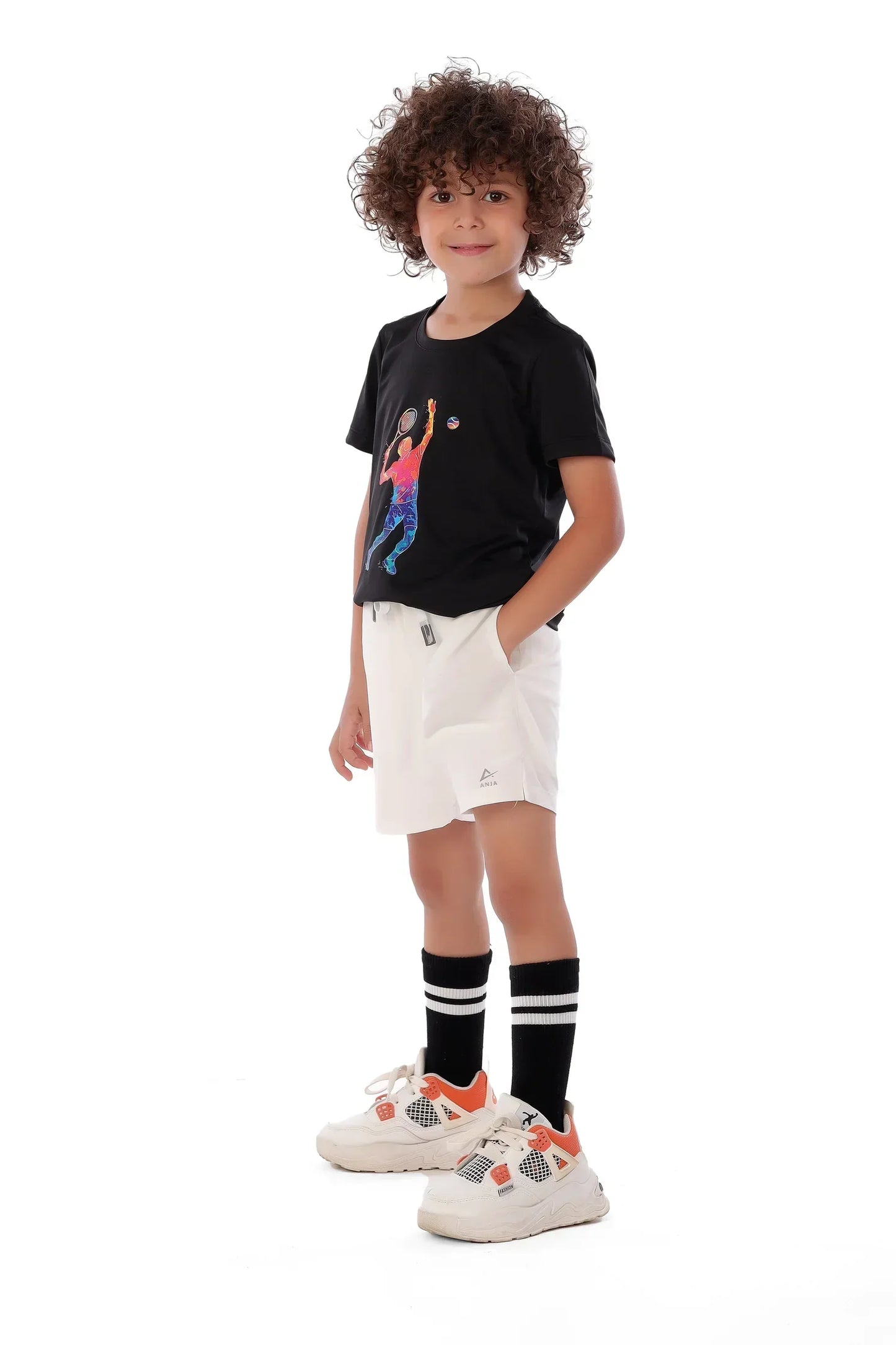 Child wearing a black t-shirt with a graphic design, white shorts, black socks with white stripes, and white sneakers on a white background.