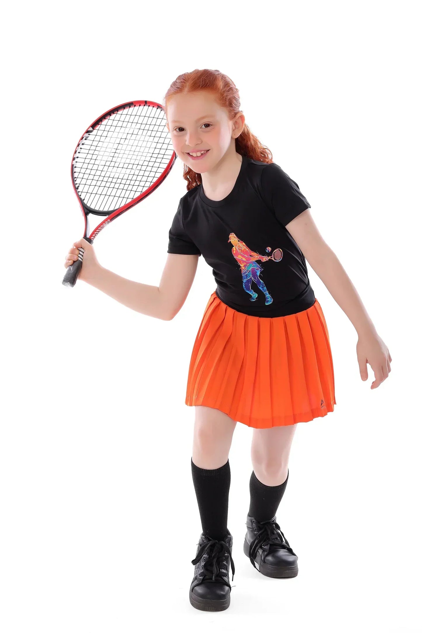 Young girl holding a tennis racket, wearing a black t-shirt with a graphic design and an orange skirt.