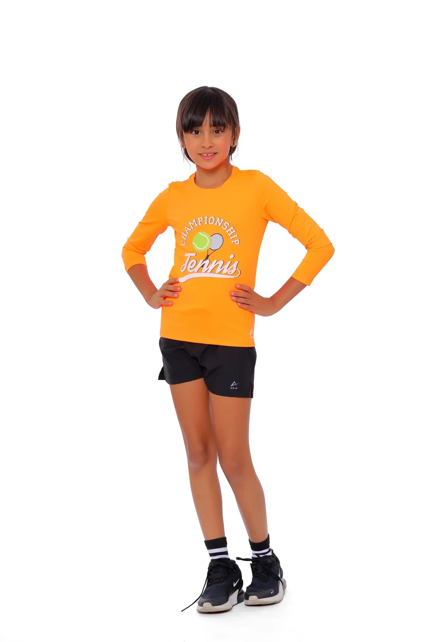 Child wearing an orange 'Champions of Tennis' shirt and black shorts on a white background