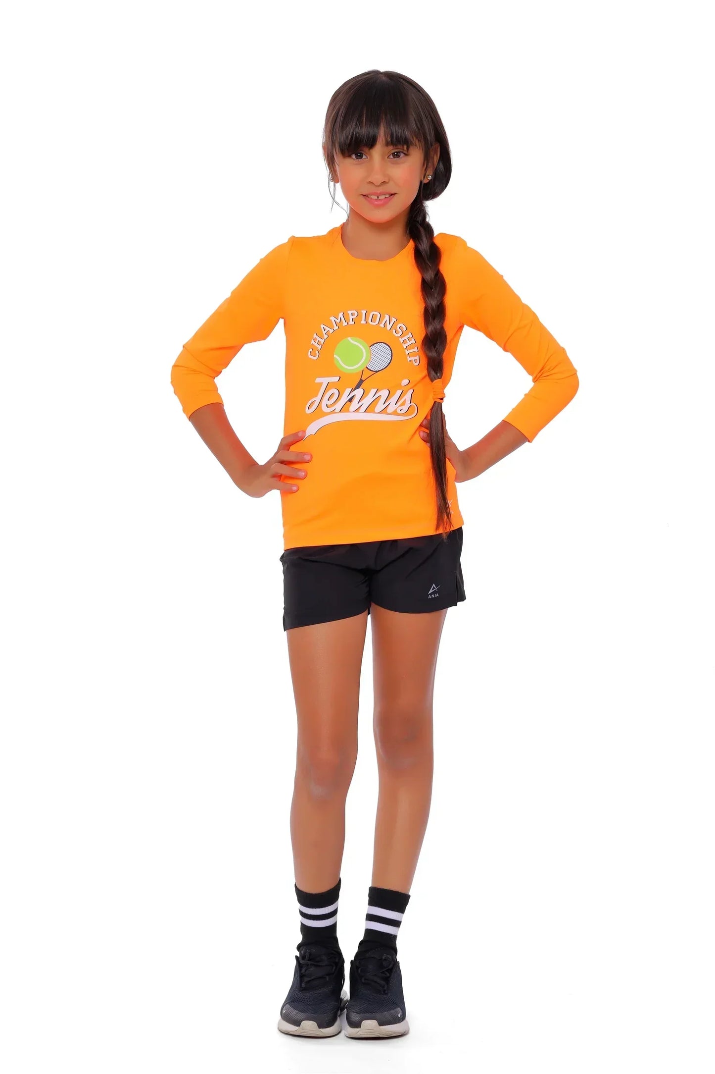 Girl wearing an orange 'Champion Tennis' shirt and black shorts on a white background