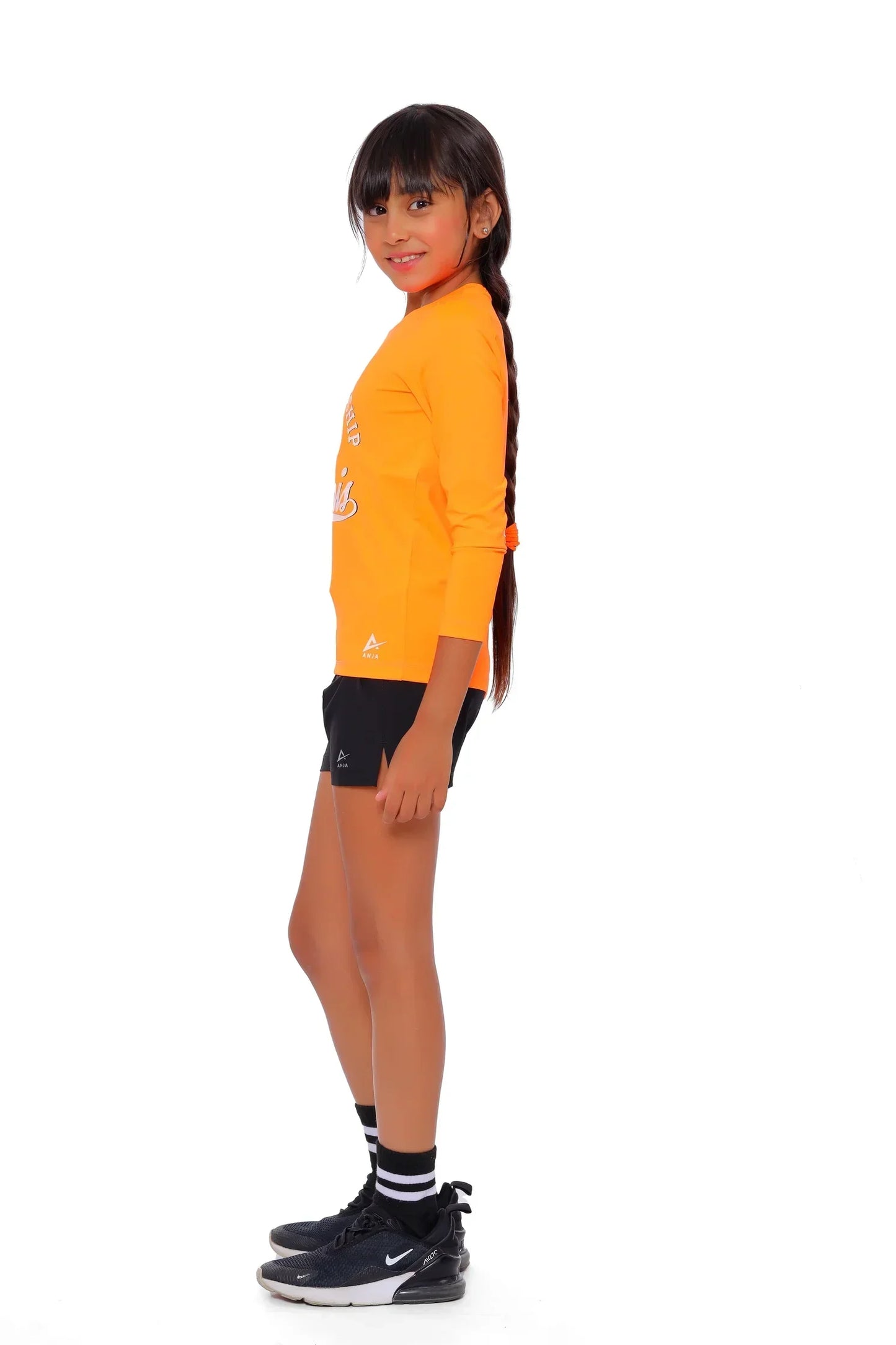 Child wearing an orange jacket and black shorts on a white background