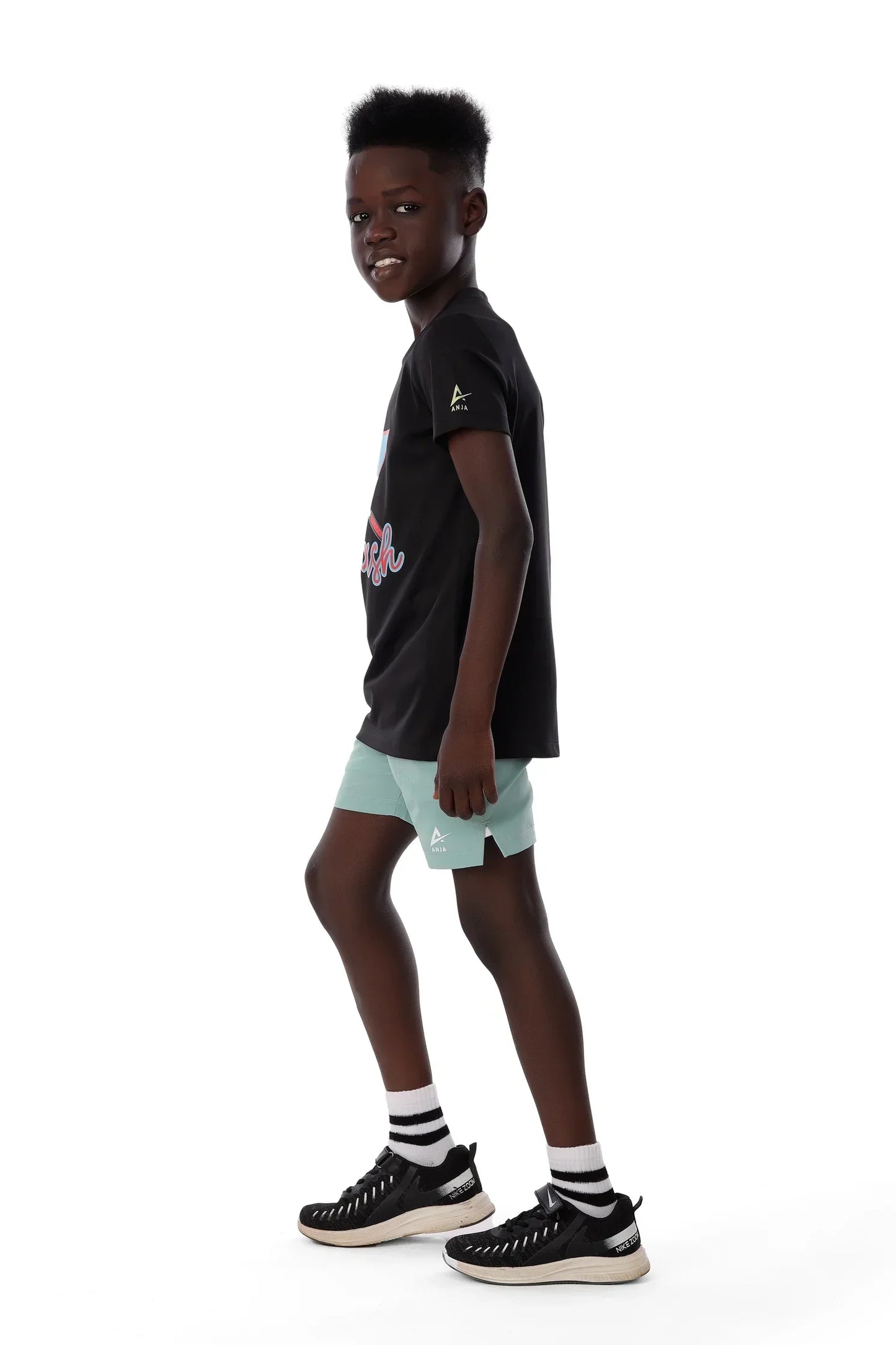 Person wearing a black t-shirt with a graphic design and light green shorts on a white background