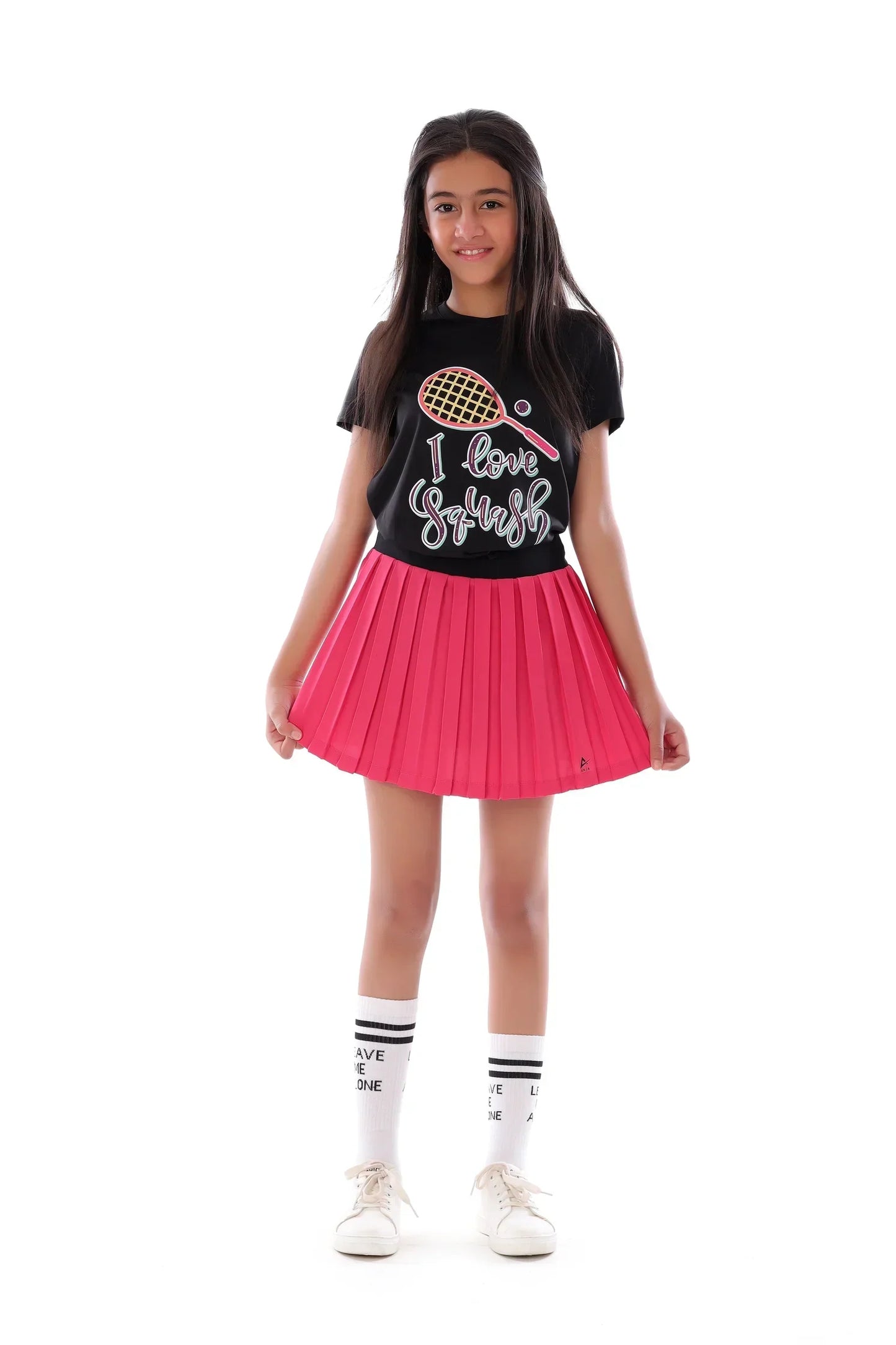 Girl wearing a black t-shirt with a graphic and pink pleated skirt on a white background