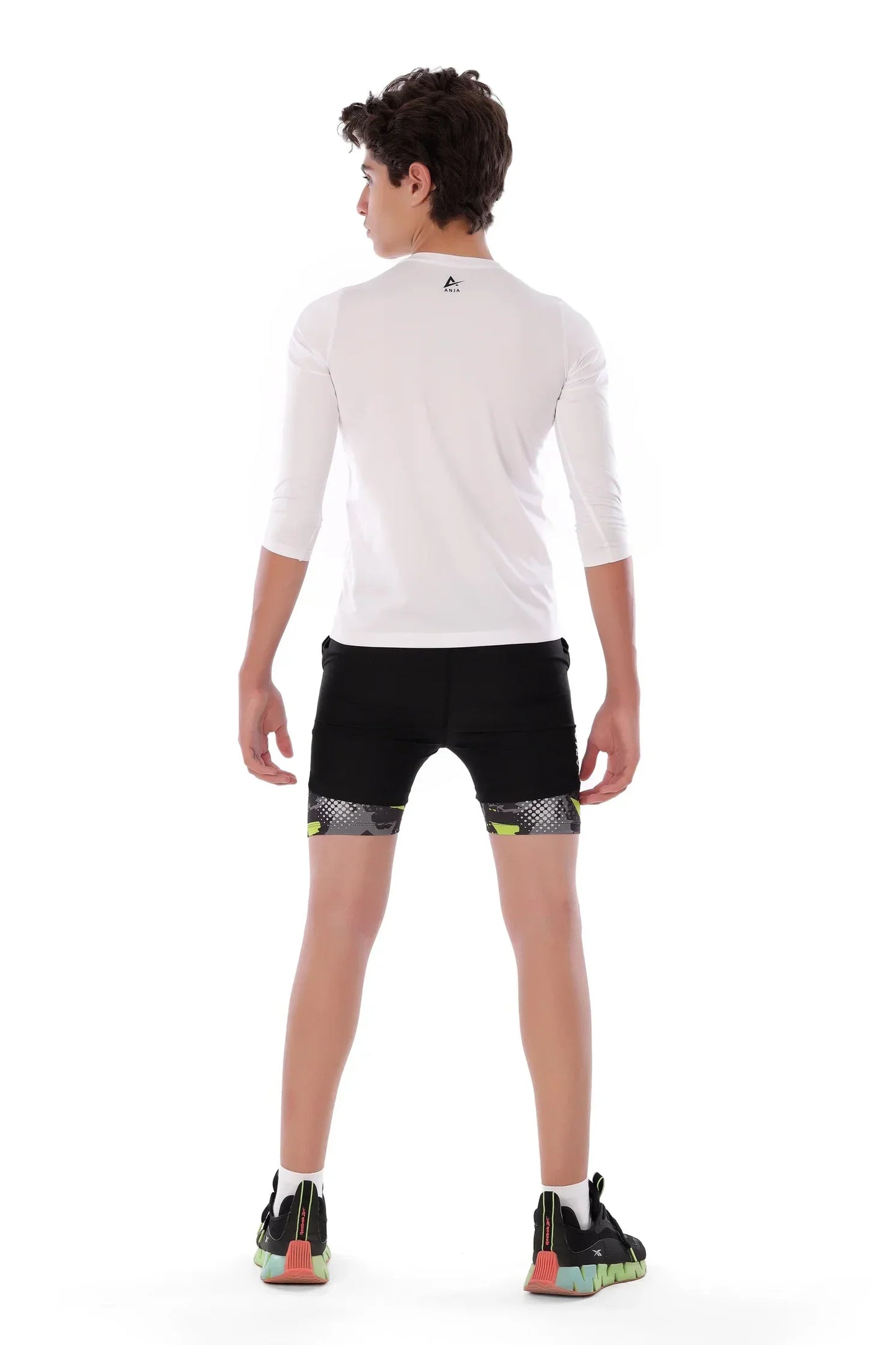 Person wearing a white long-sleeve athletic shirt and black shorts on a white background