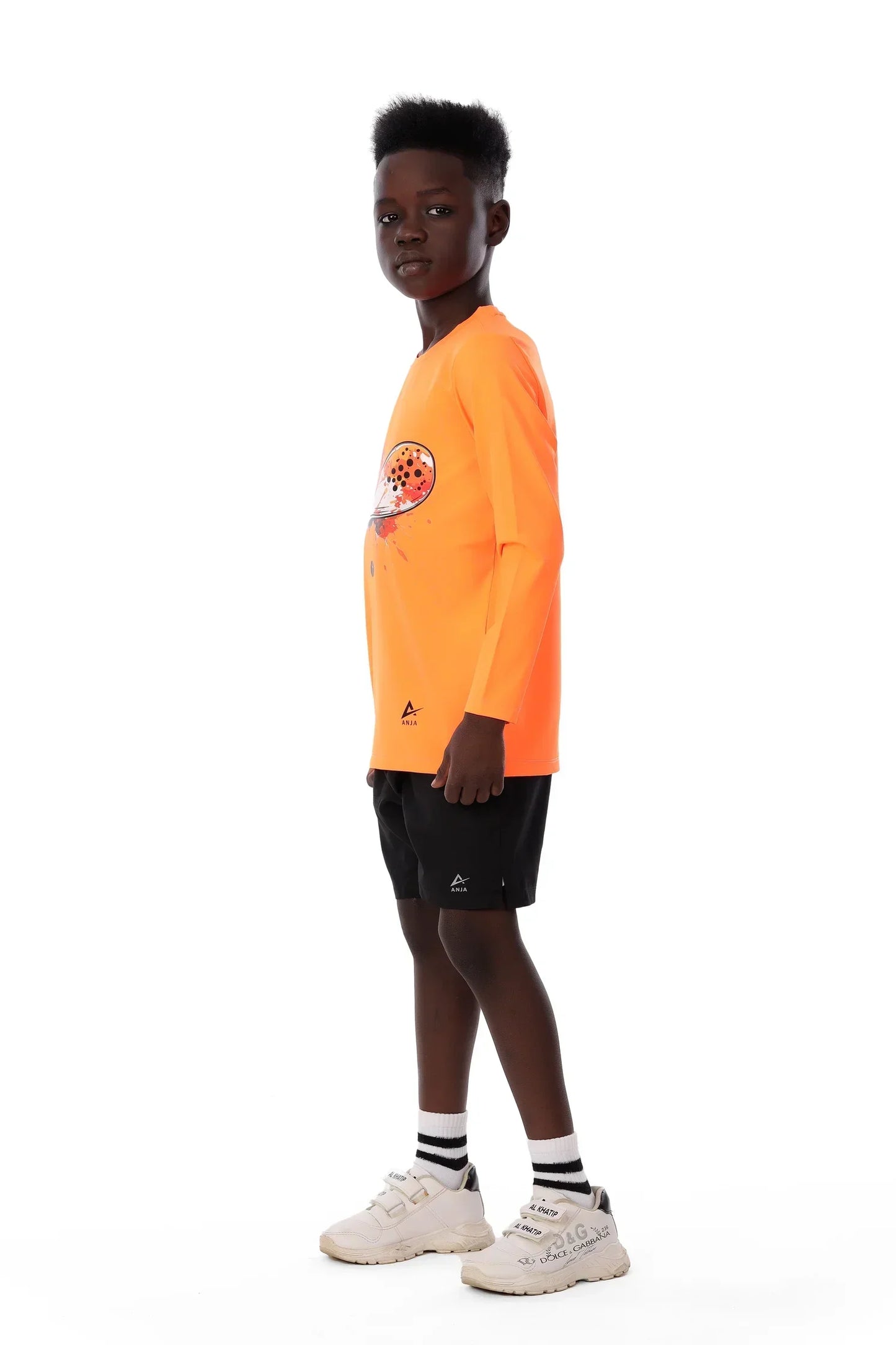 Person wearing an orange long-sleeve shirt and black shorts on a white background