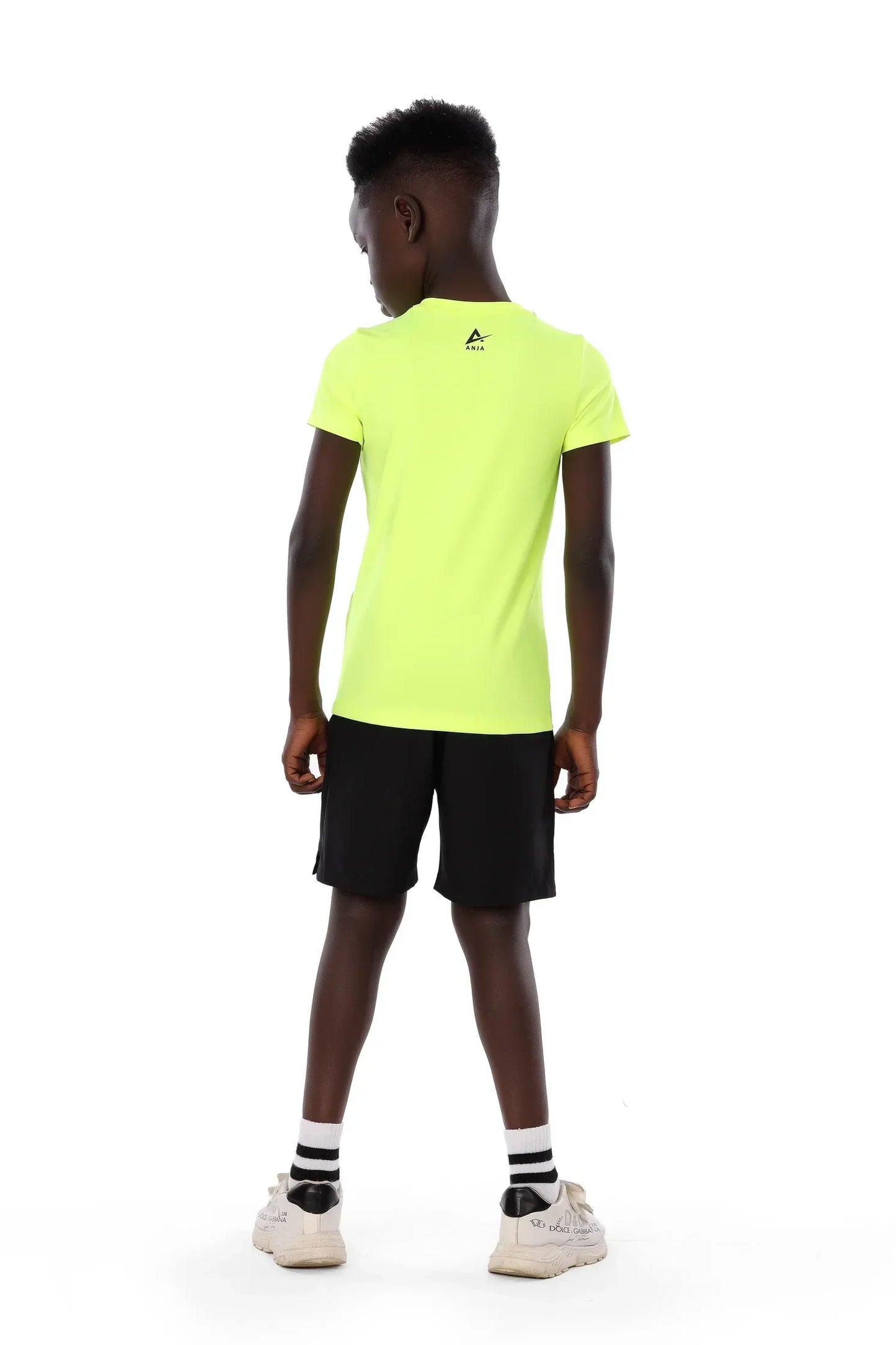 Person wearing a bright yellow t-shirt and black shorts on a white background
