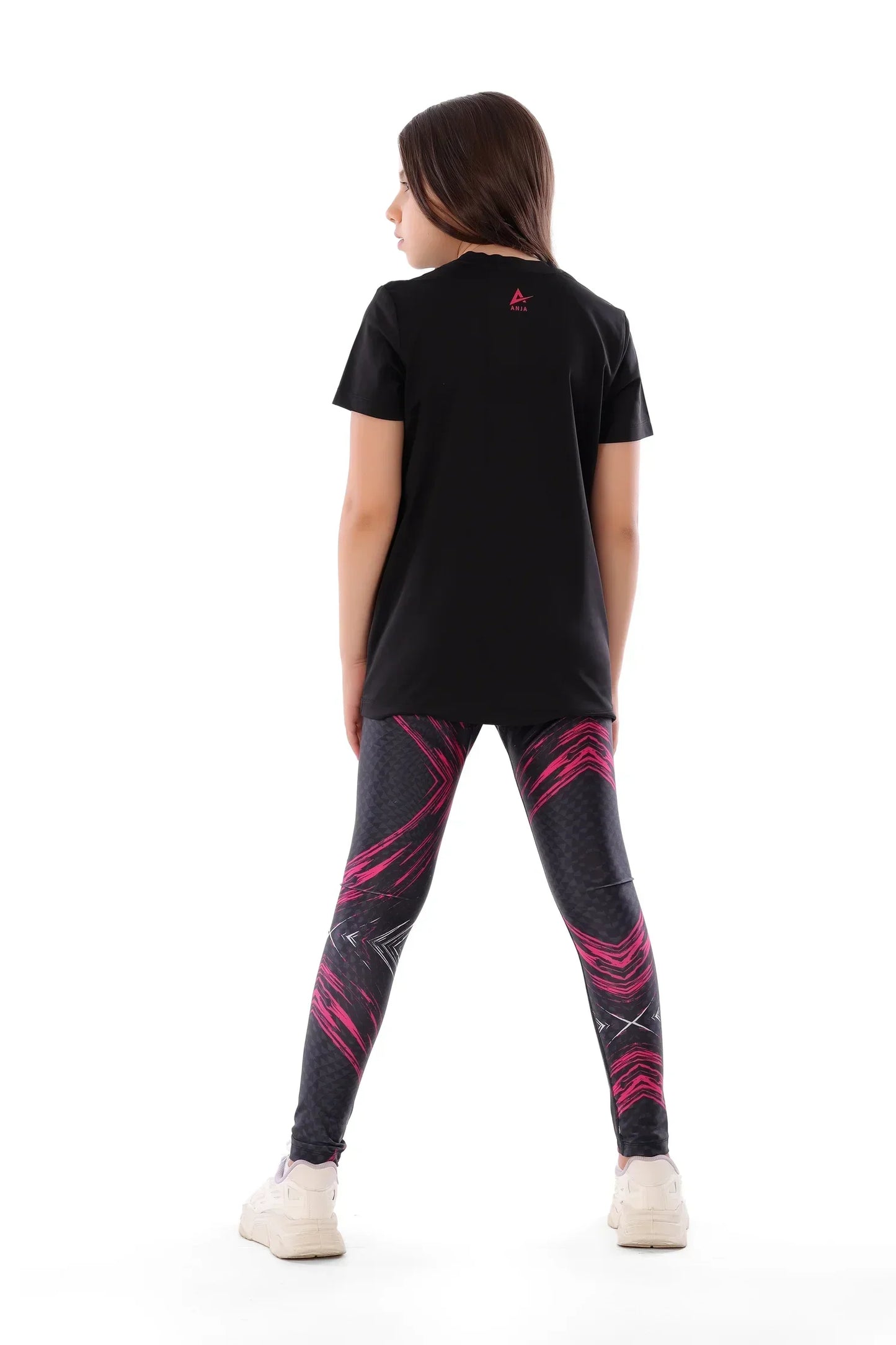 Person wearing a black t-shirt and black leggings with pink designs on a white background
