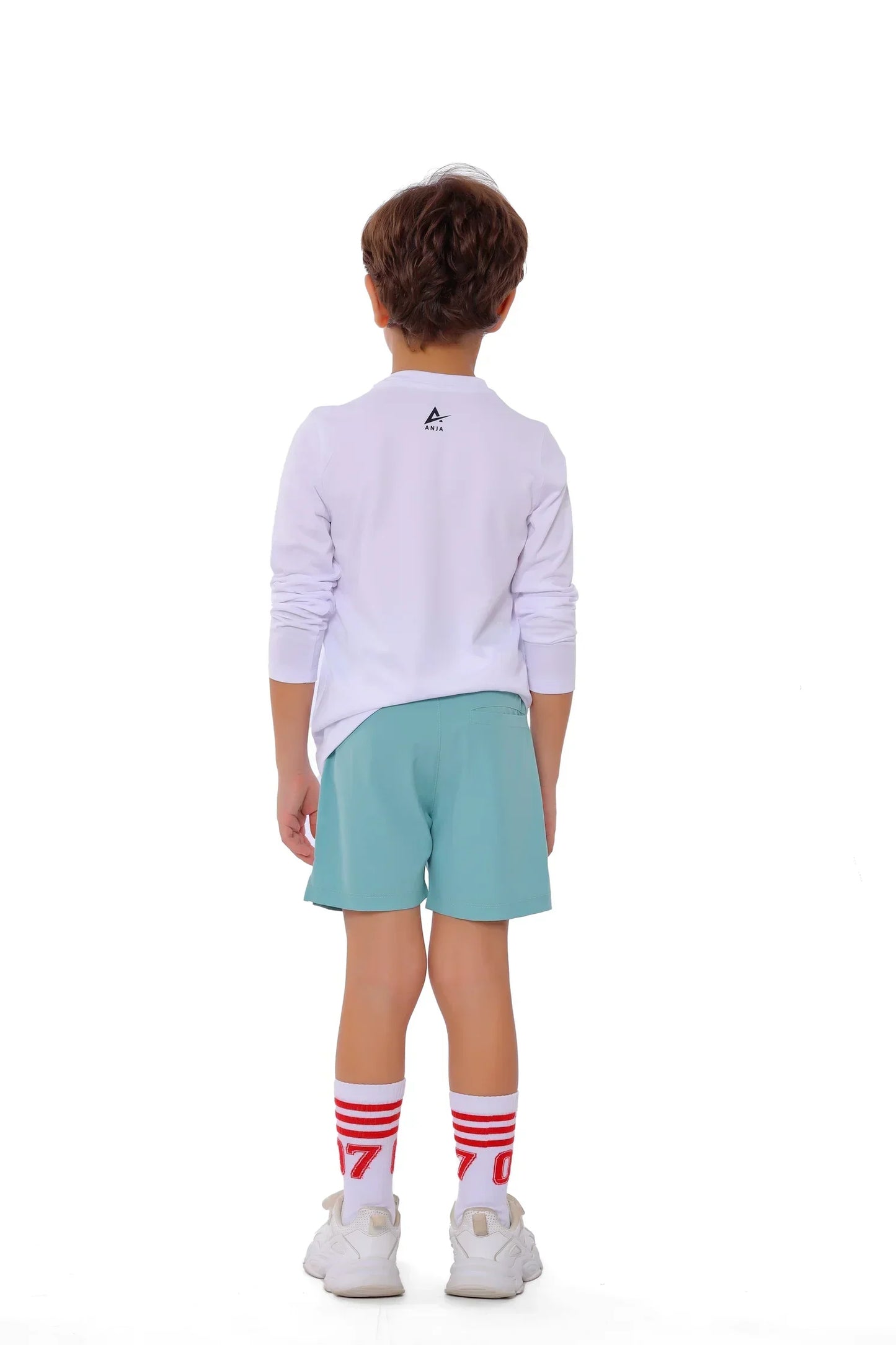 Child wearing a white long-sleeve shirt and light green shorts on a white background
