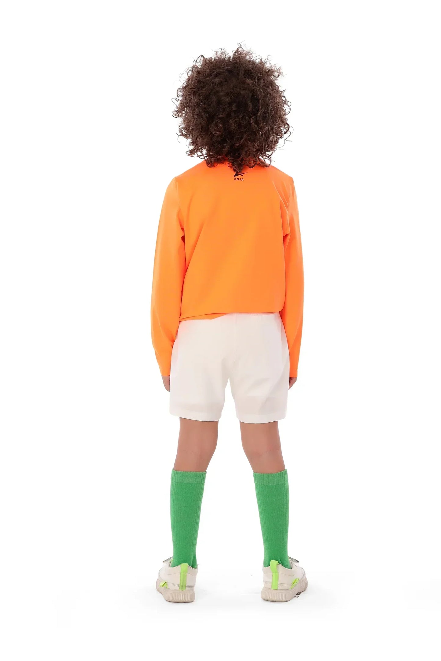 Person wearing an orange long-sleeve shirt, white shorts, and green socks on a white background