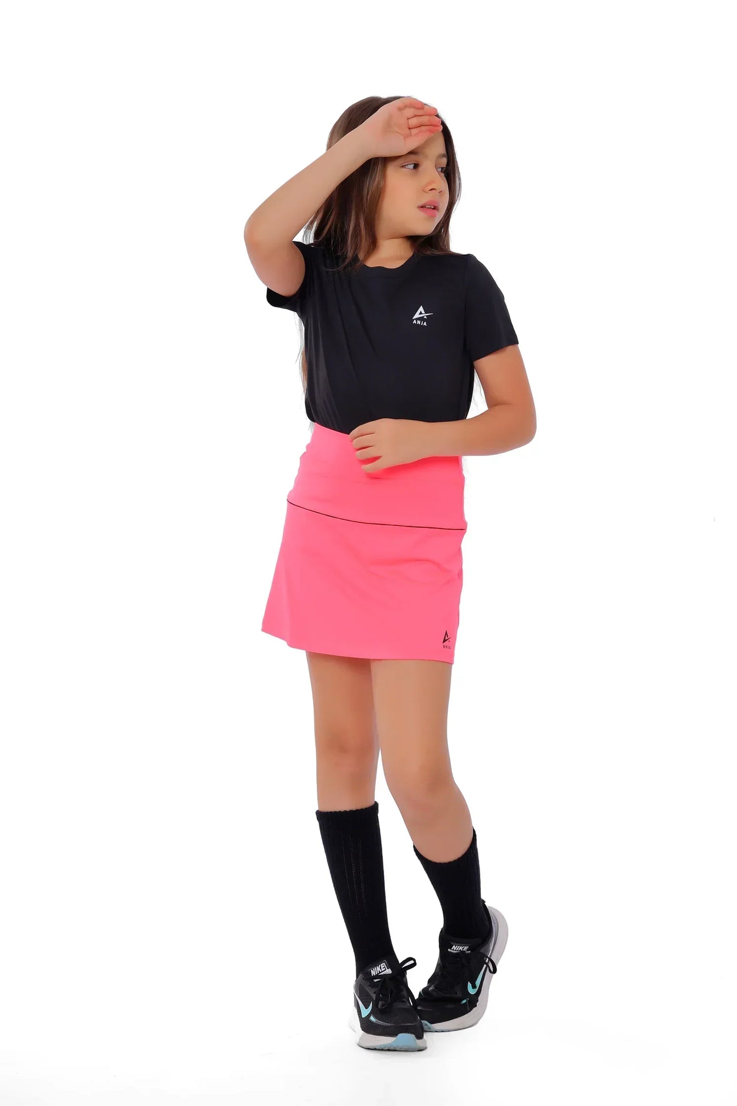 Child wearing a black t-shirt and pink skirt on a white background