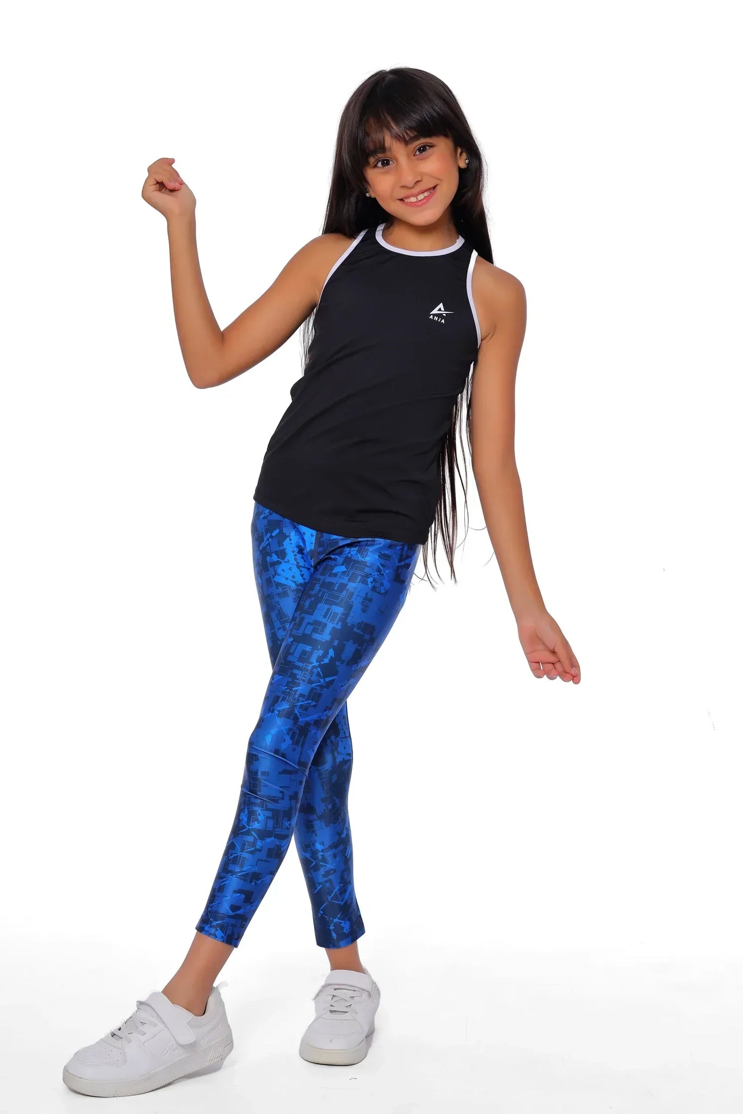 Young girl wearing a black tank top and blue patterned leggings on a white background