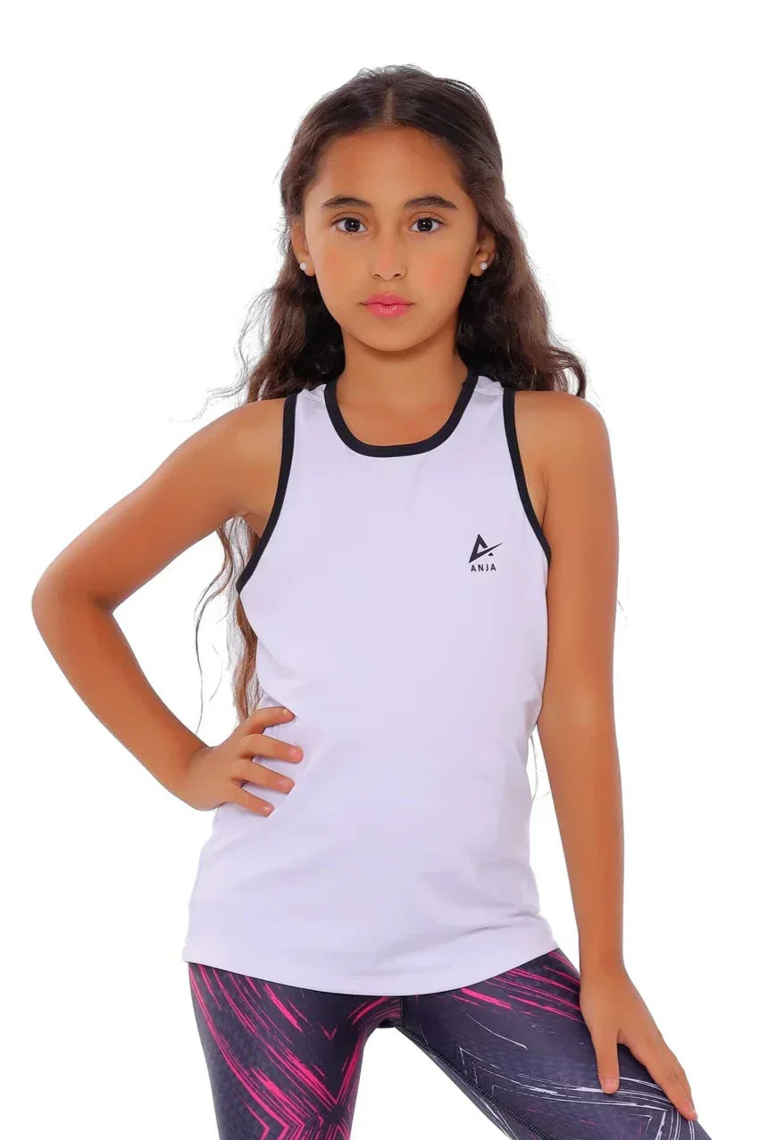 Young girl wearing a white tank top with a logo and patterned leggings on a white background