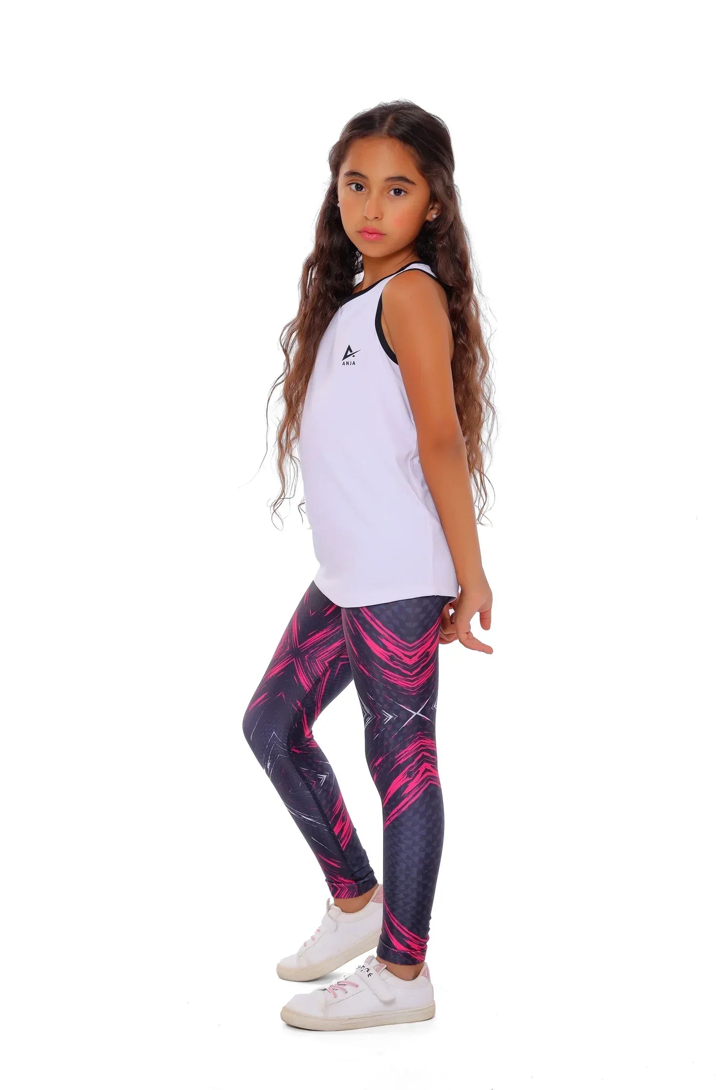 Young girl wearing a white tank top and patterned leggings on a white background