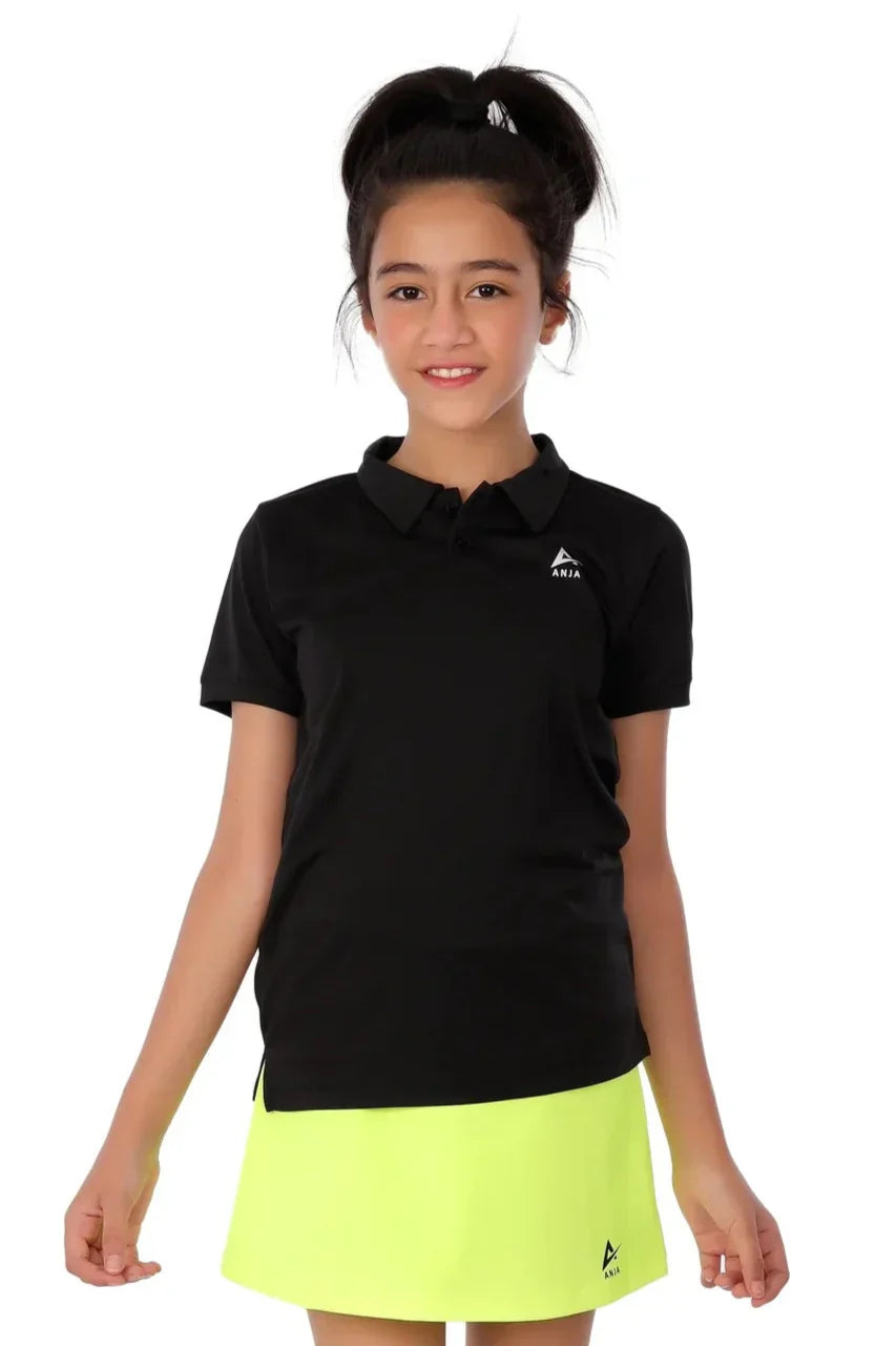 Young girl wearing a black polo shirt and yellow skirt with a brand logo on a white background