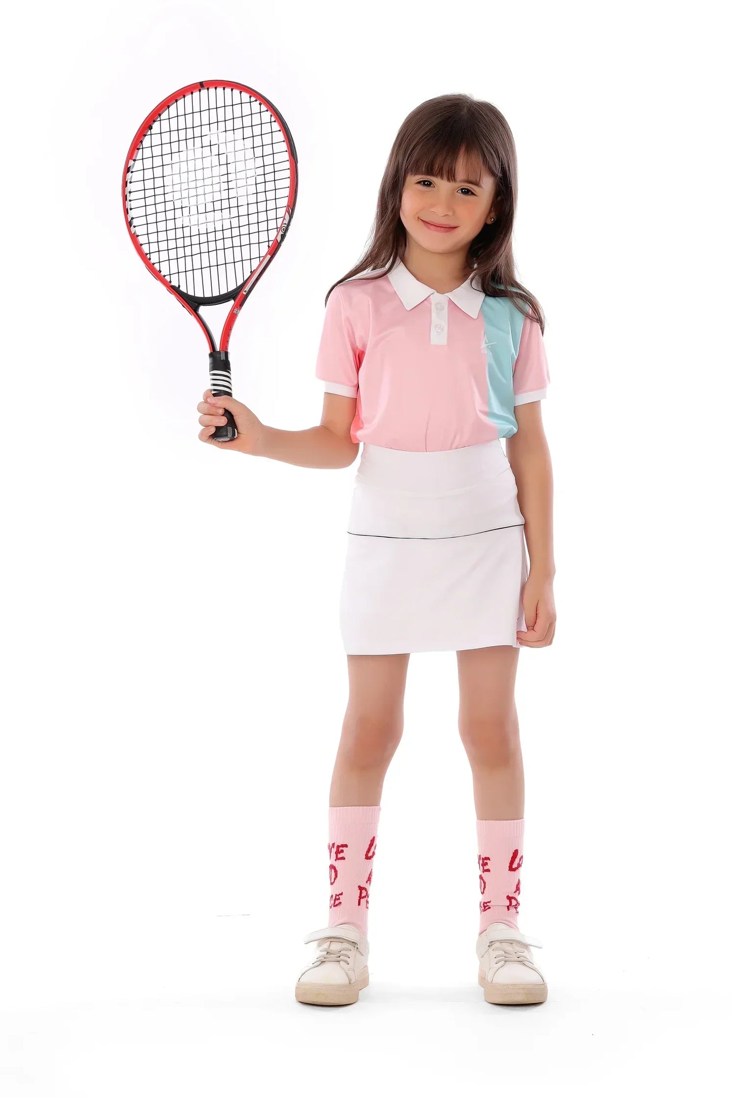 Young girl in tennis outfit holding a racket on a white background
