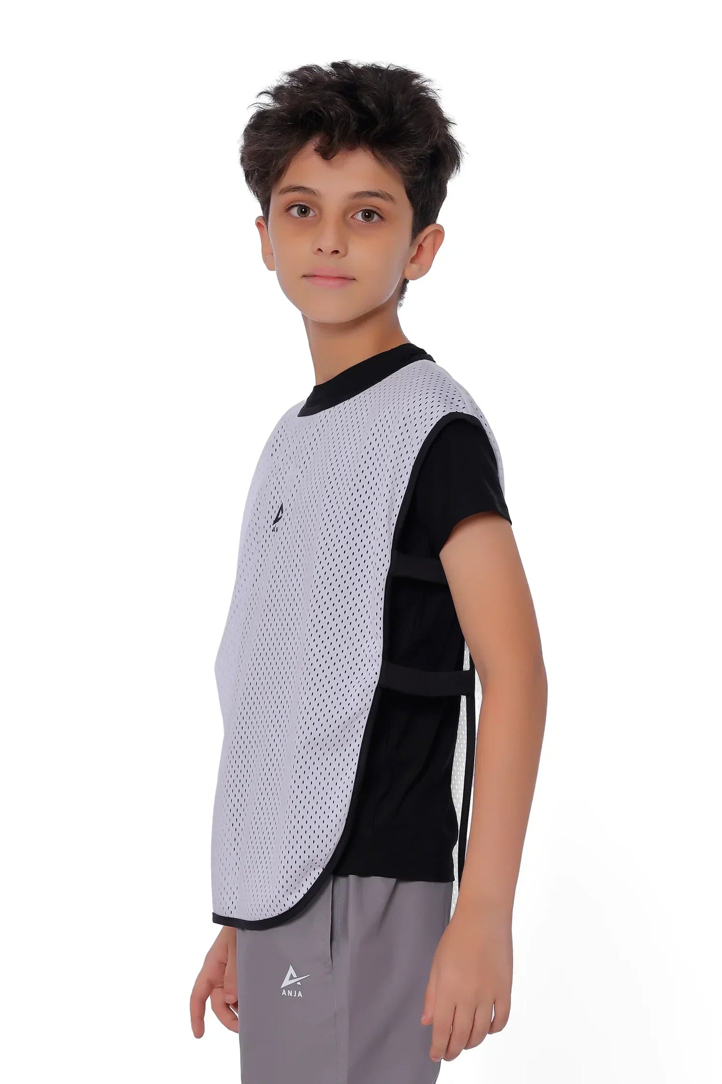 Child wearing a black and white sports vest over a black shirt on a white background