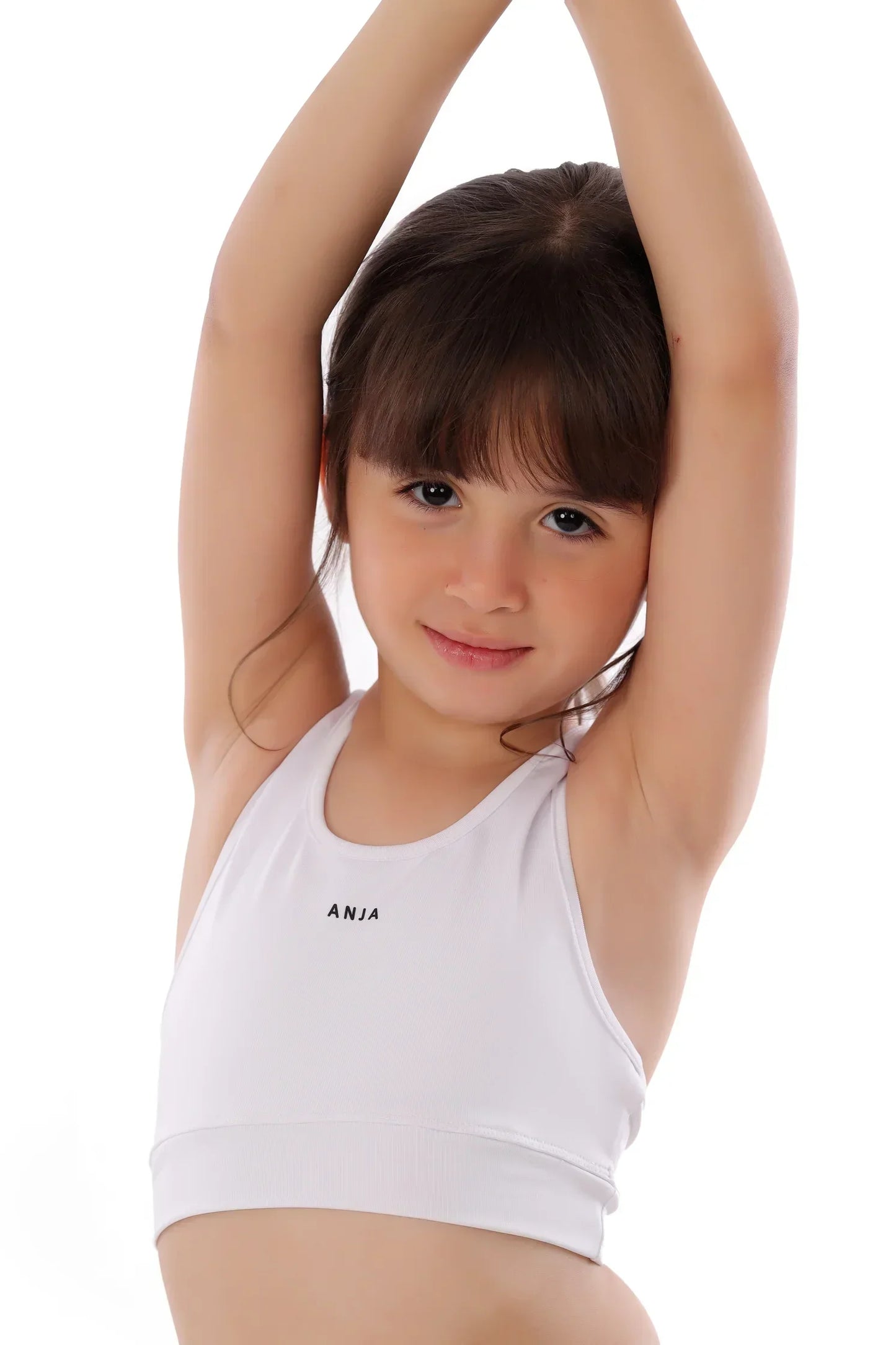 Young girl wearing a white tank top with 'ANIA' branding on a white background