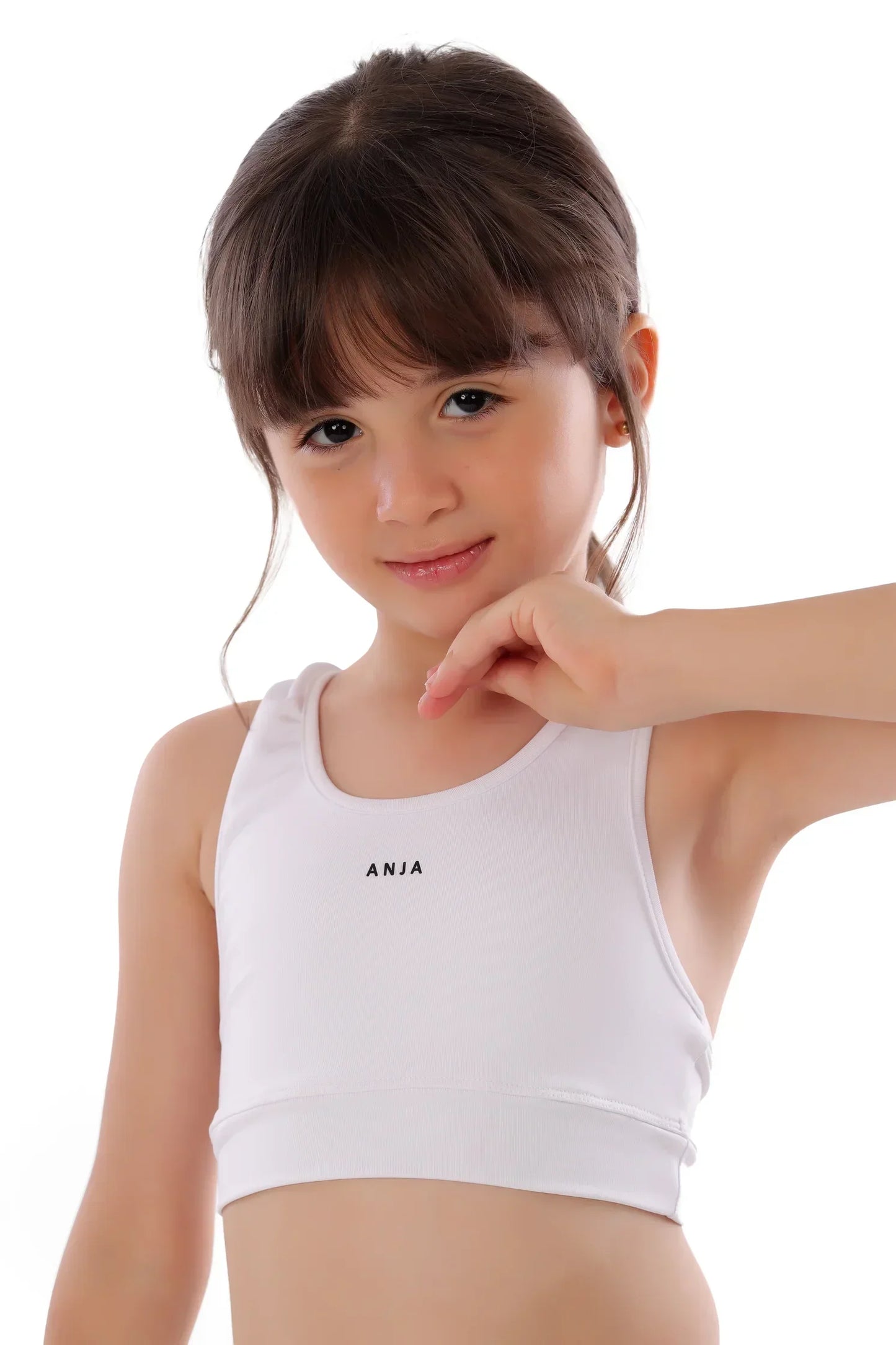 Young girl wearing a white tank top with 'ANJA' branding on a white background