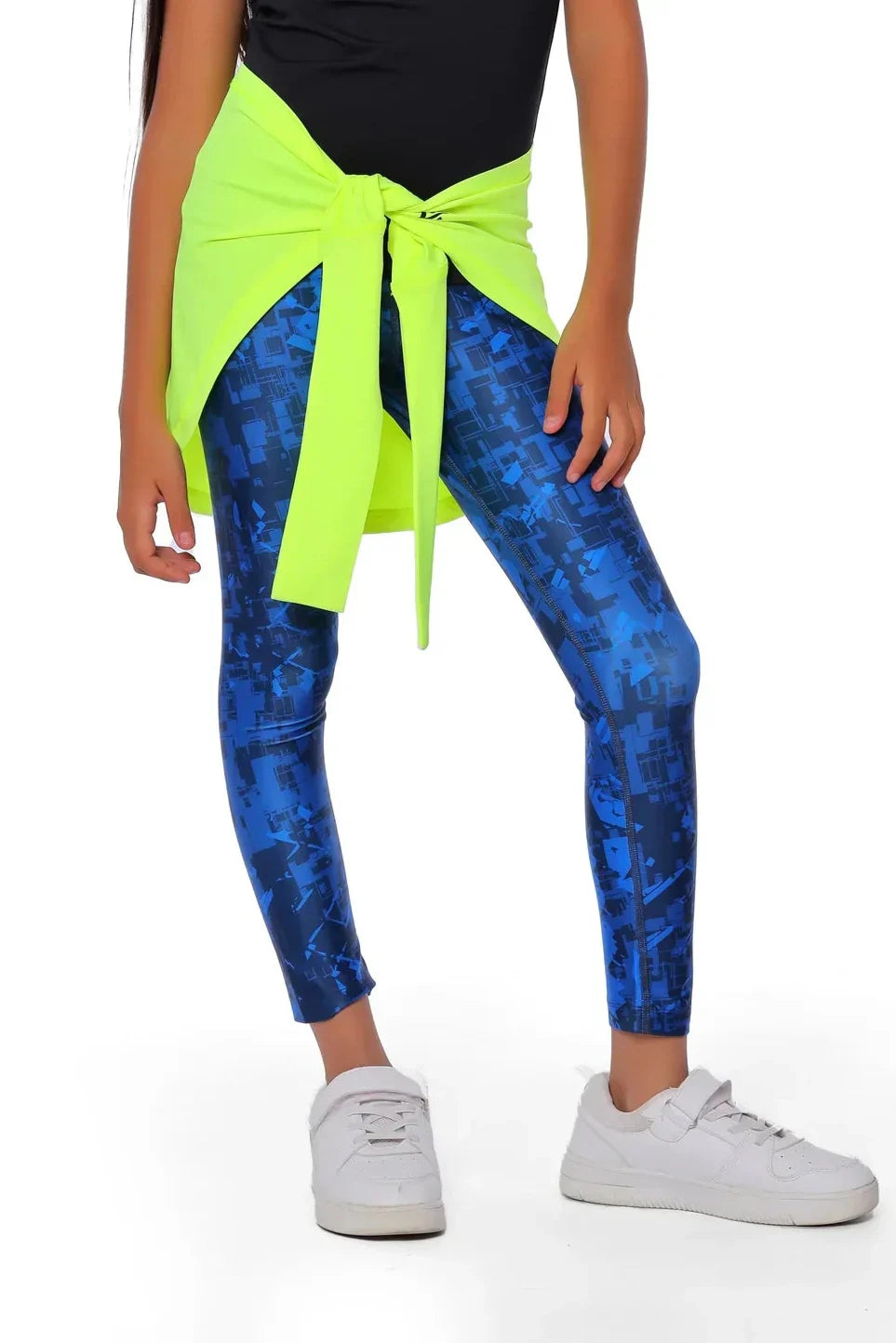 Person wearing blue tie-dye leggings with a neon green top and white sneakers on a white background
