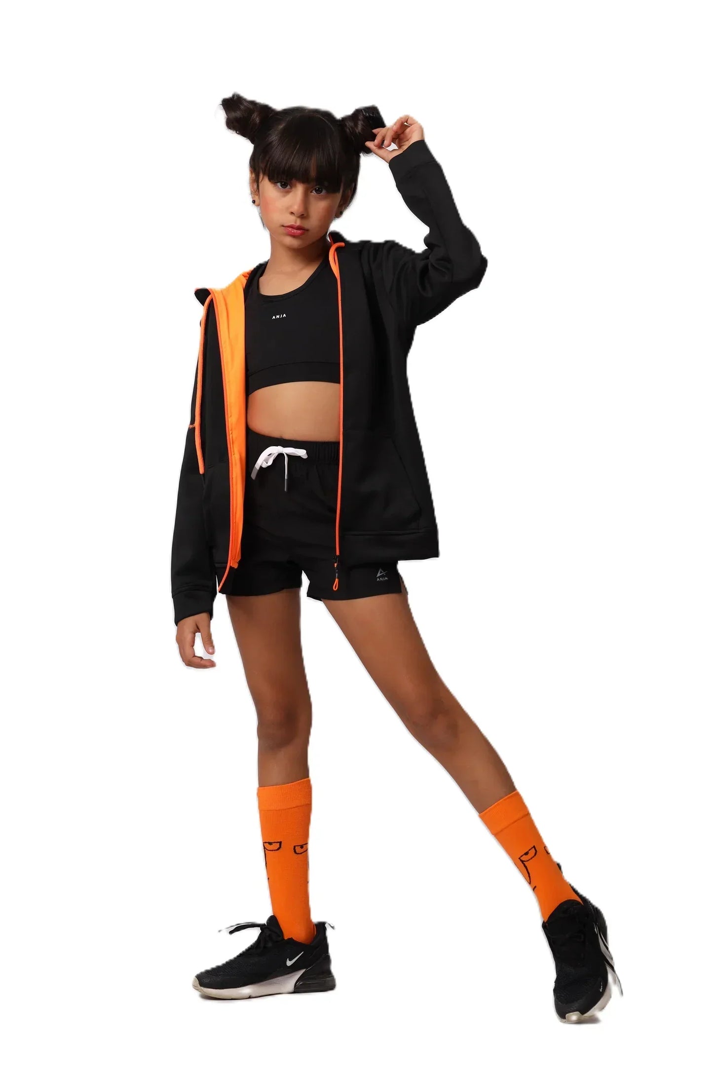 Person wearing a black and orange athletic outfit with matching socks on a white background