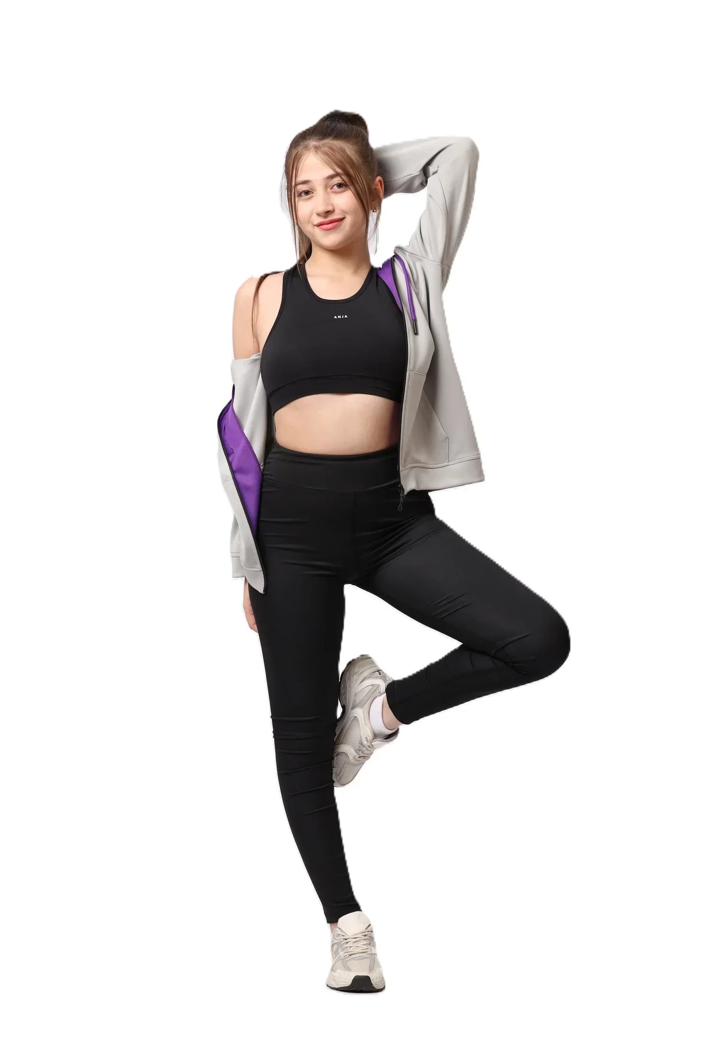 Woman in black athletic wear with a gray jacket on a white background