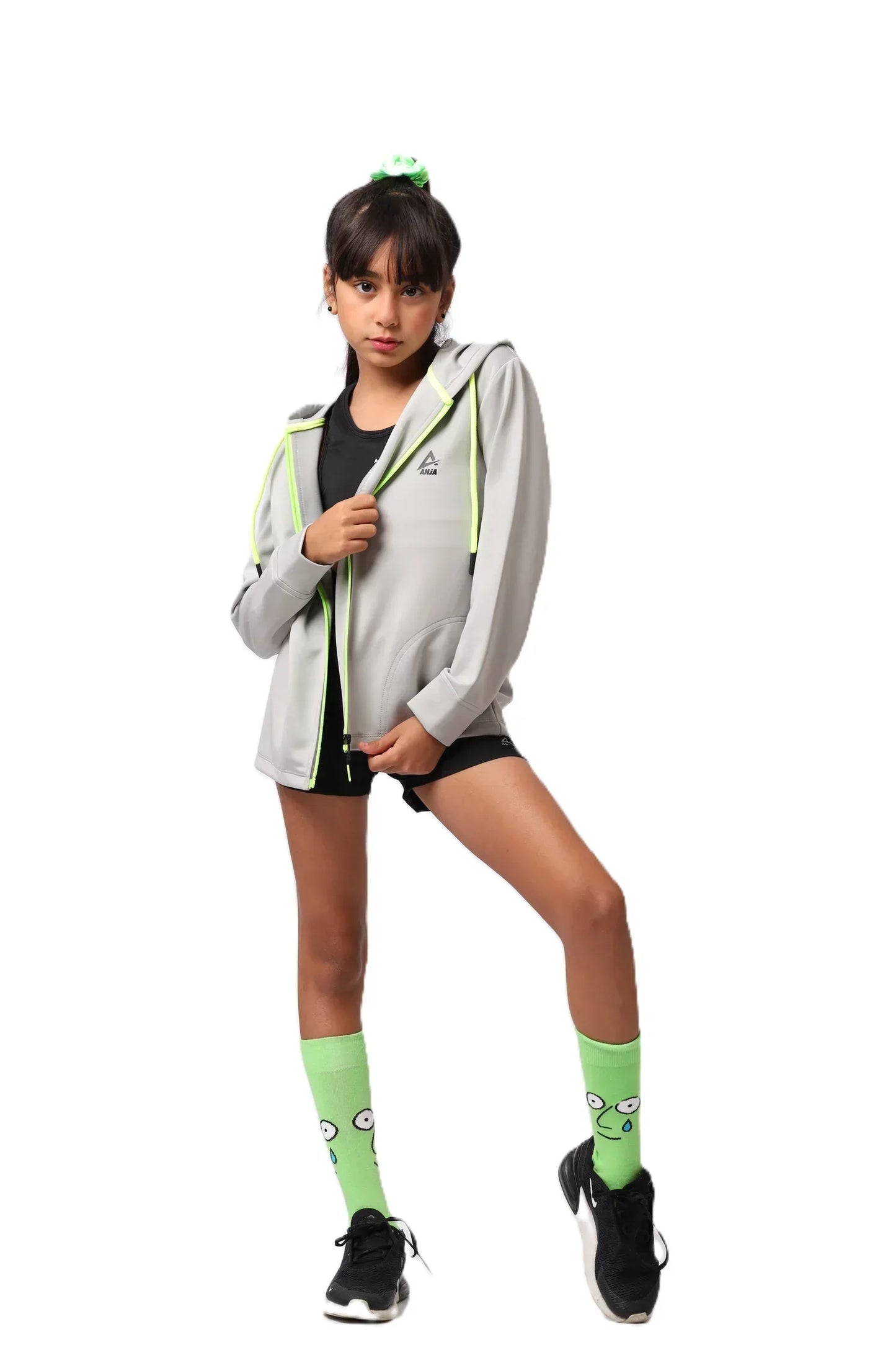 girl wearing a gray hoodie, black shorts, and green socks with a white background