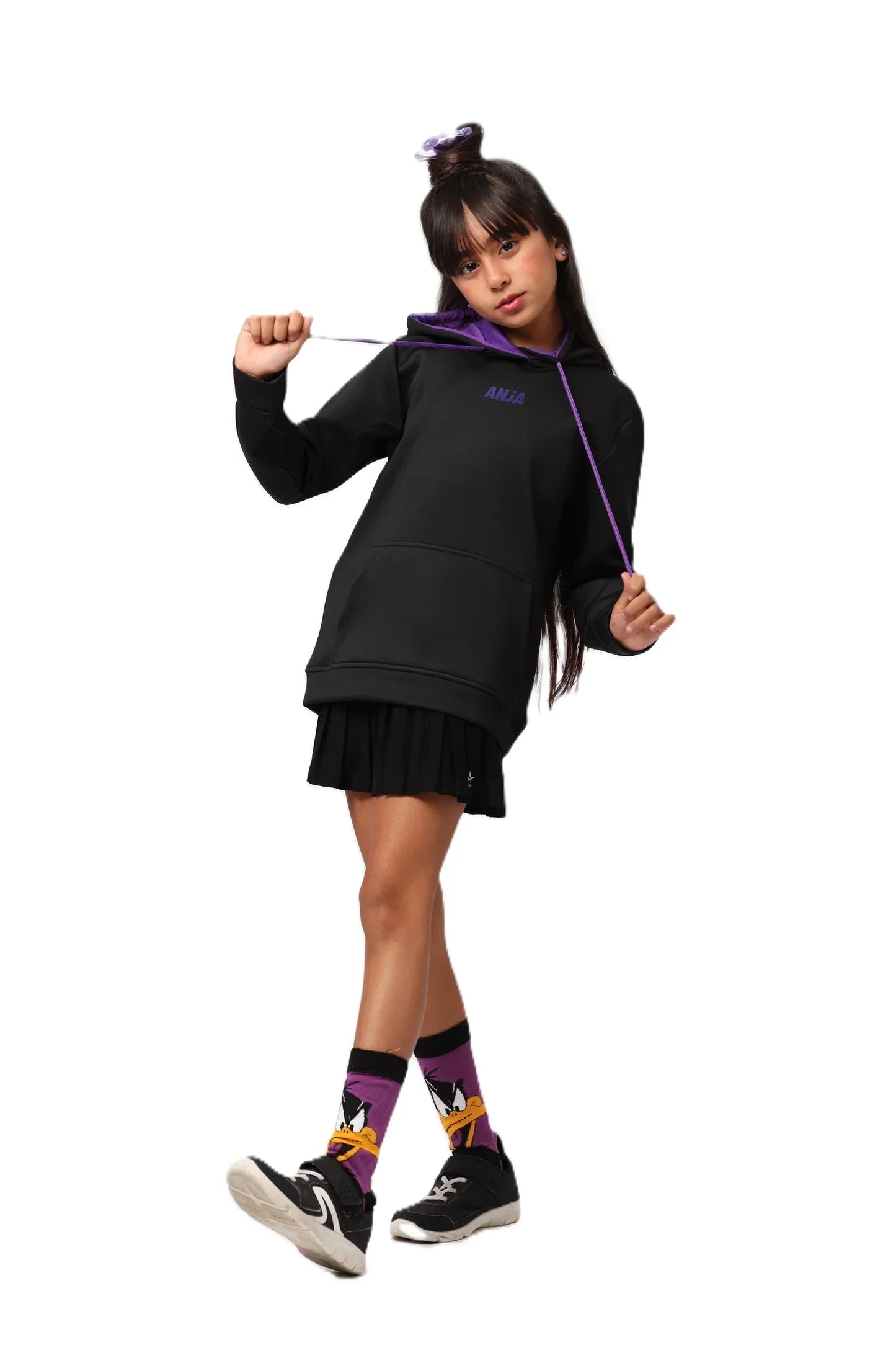 Person wearing a black hoodie and skirt with colorful socks on a white background