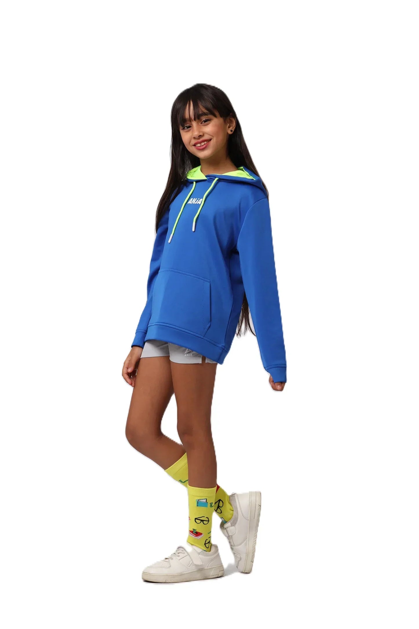 Person wearing a blue hoodie with a green hood, white shorts, yellow socks, and white shoes on a white background