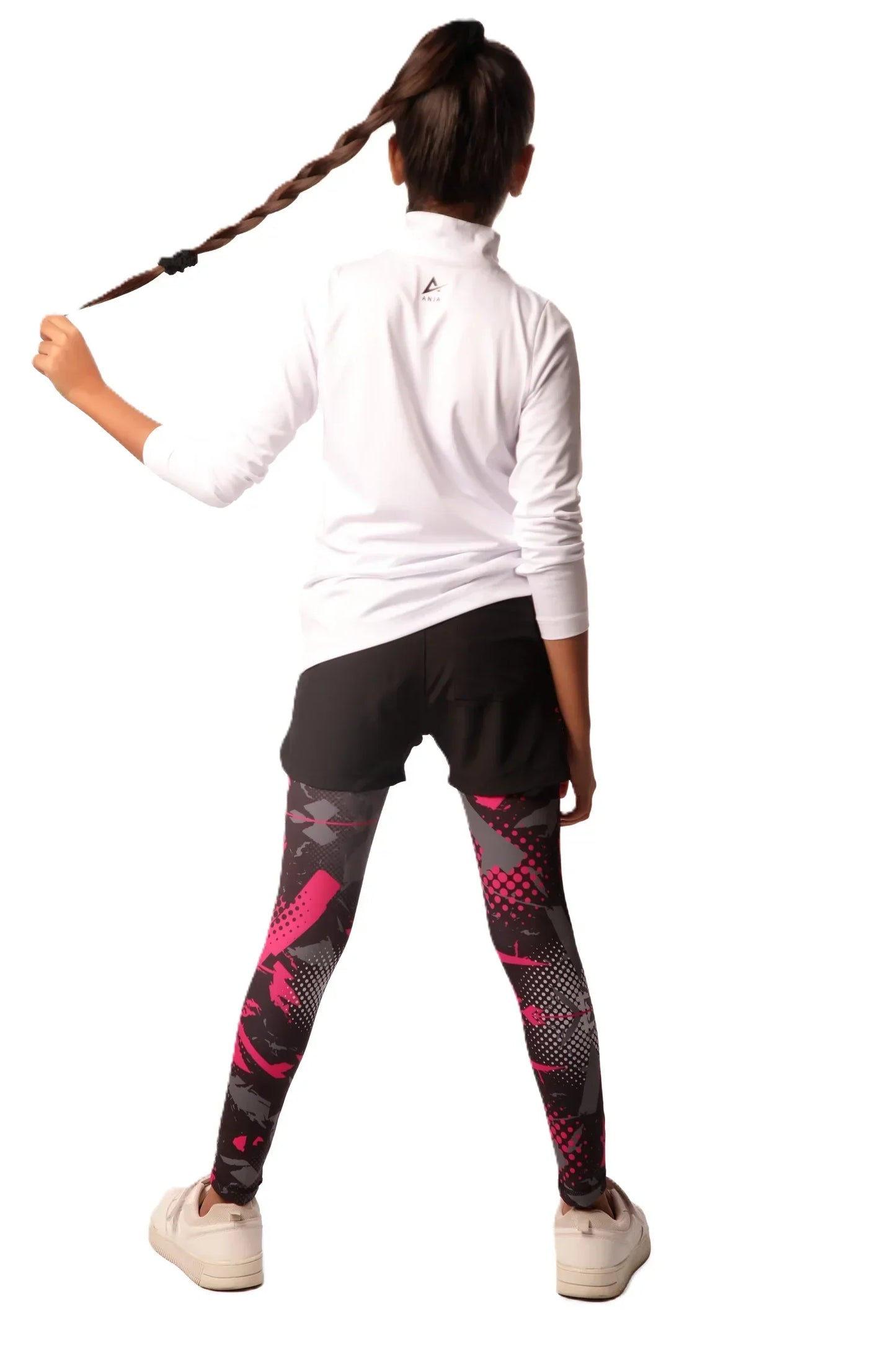 Person wearing a white long-sleeve top and black leggings with pink patterns on a white background