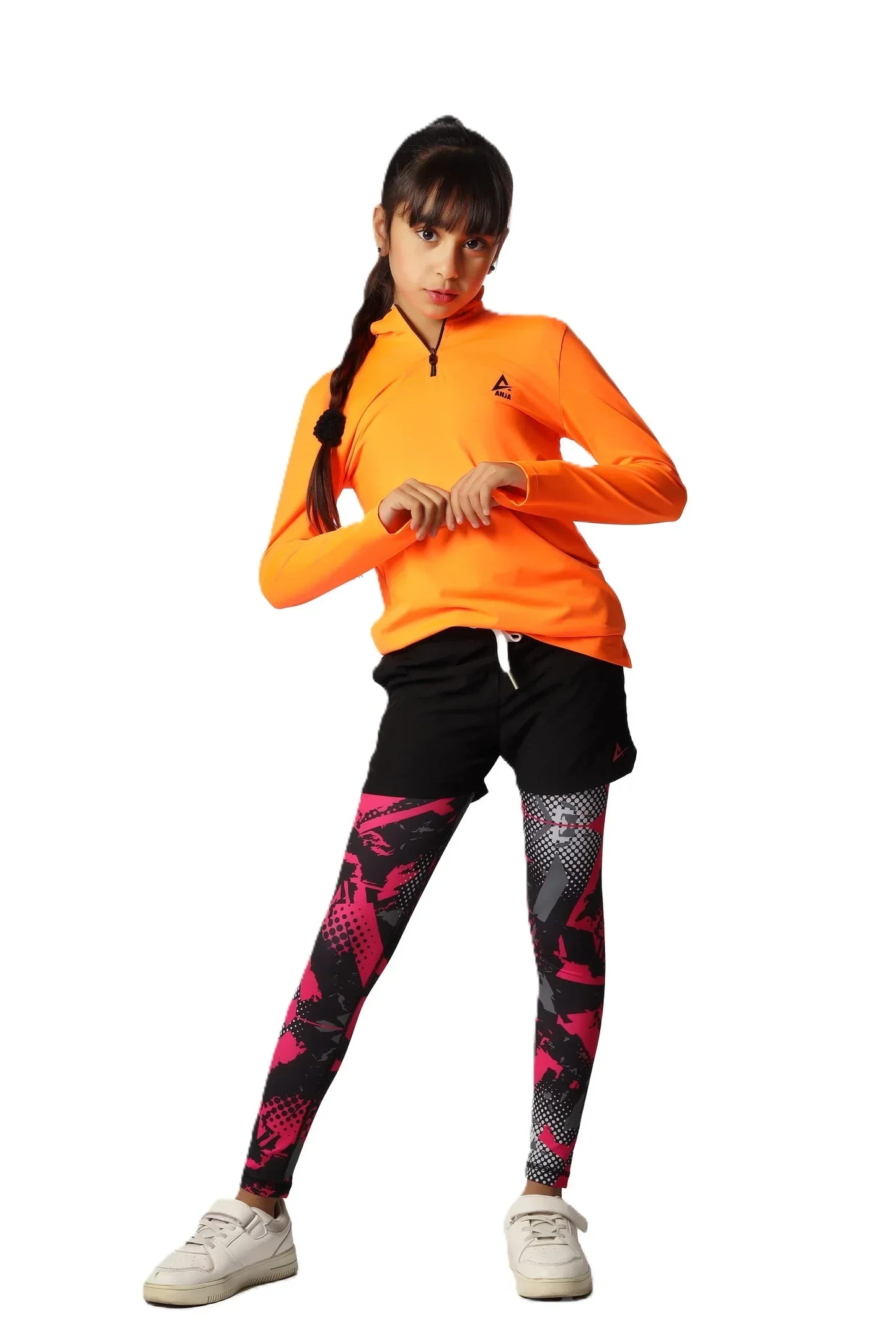 Child wearing an orange long-sleeve shirt and black leggings with pink patterns on a white background