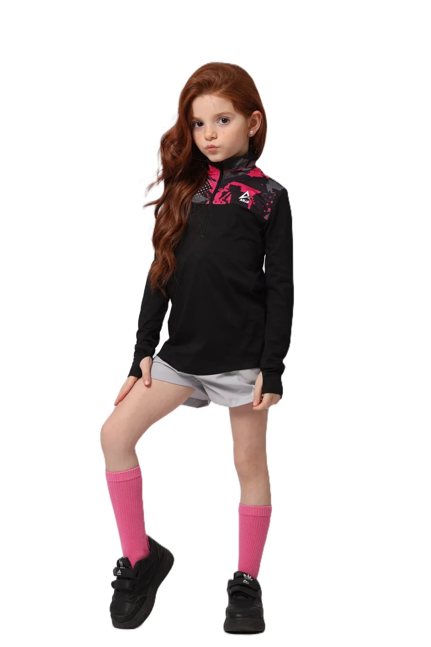 Young girl wearing a black long-sleeve shirt with pink designs, white shorts, pink socks, and black shoes on a white background.