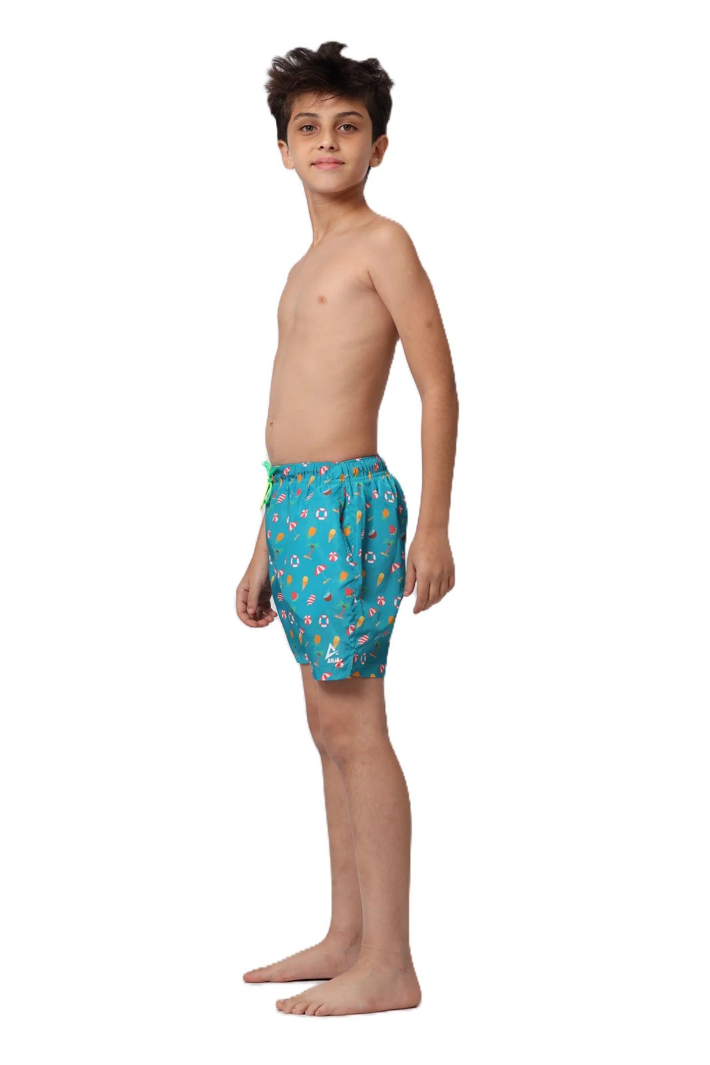 Young boy wearing teal swim shorts with a colorful pattern on a white background
