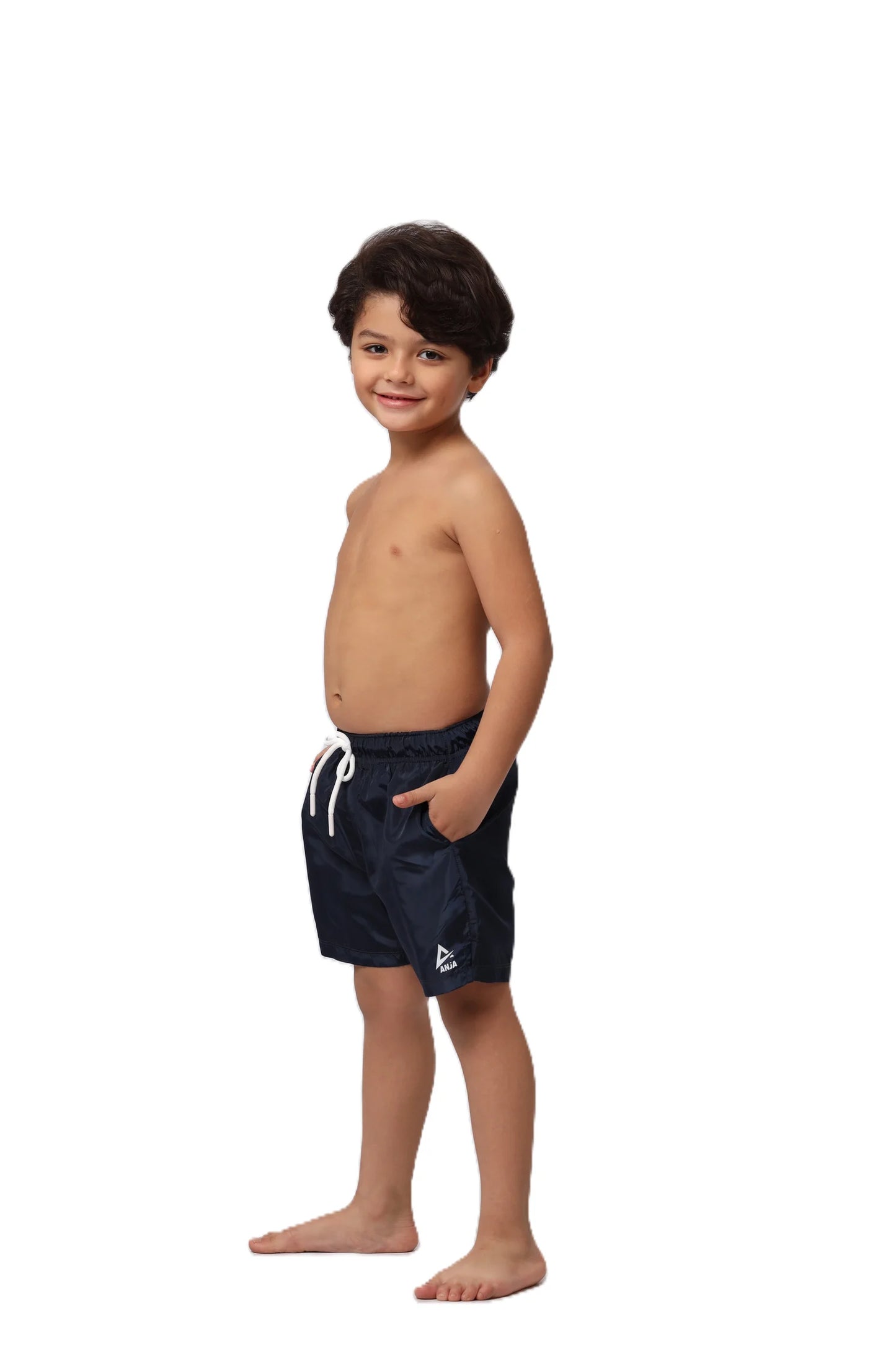 Young boy wearing navy swim shorts on a white background