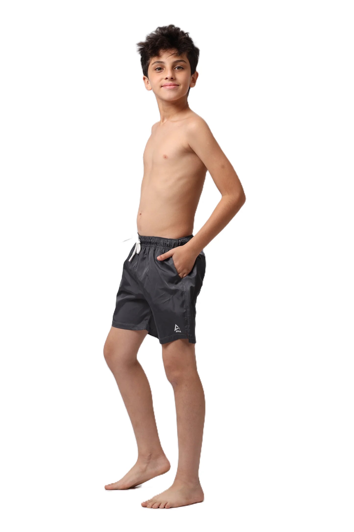 Young boy wearing dark gray swim shorts on a white background