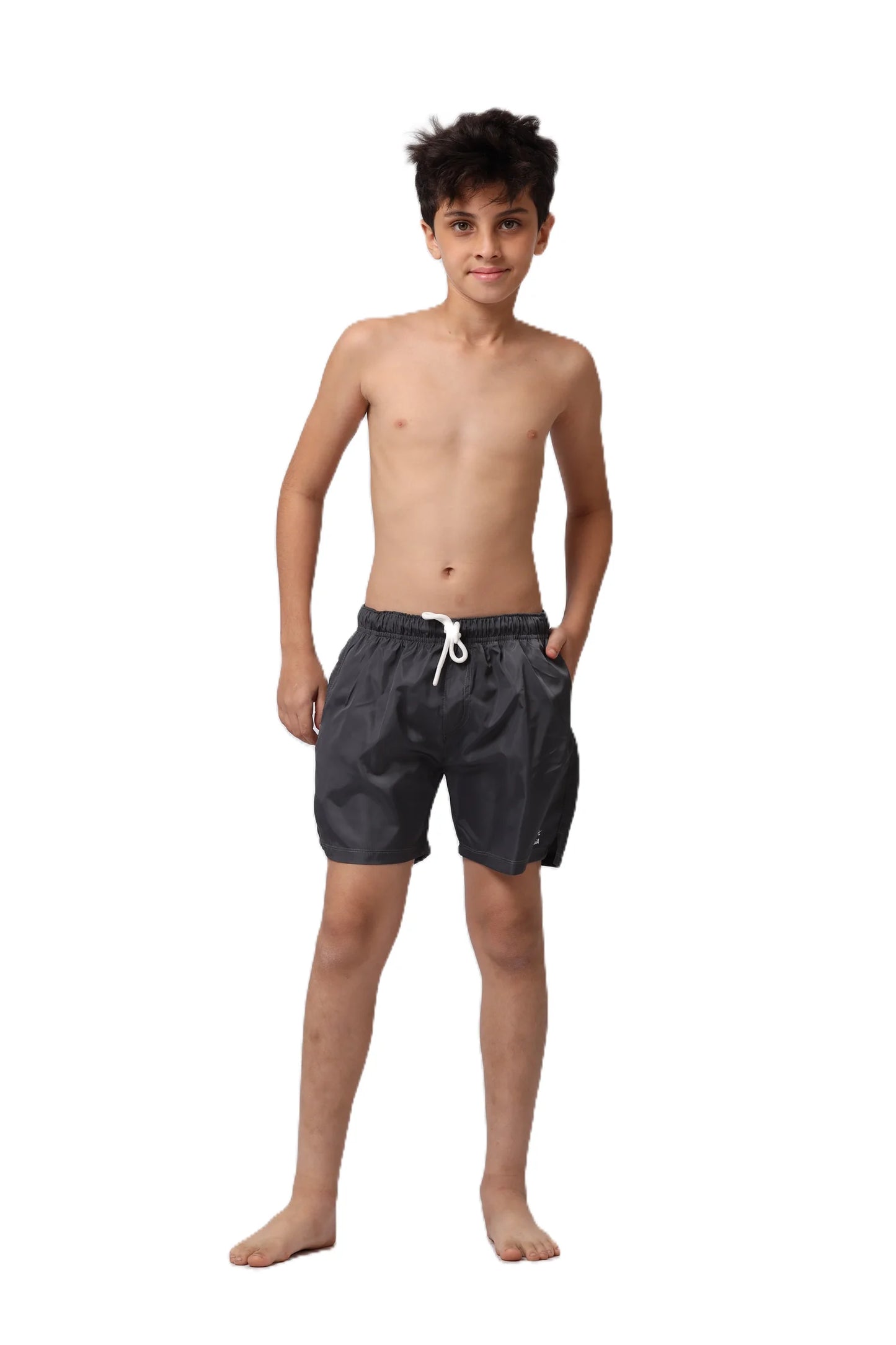Young boy wearing black swim shorts on a white background