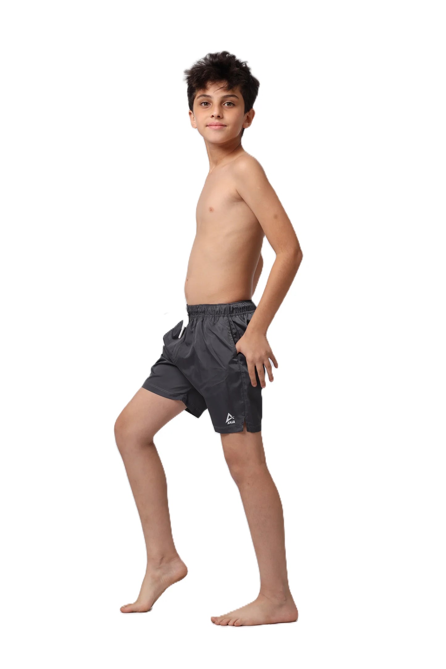 Young boy wearing black swim shorts on a white background