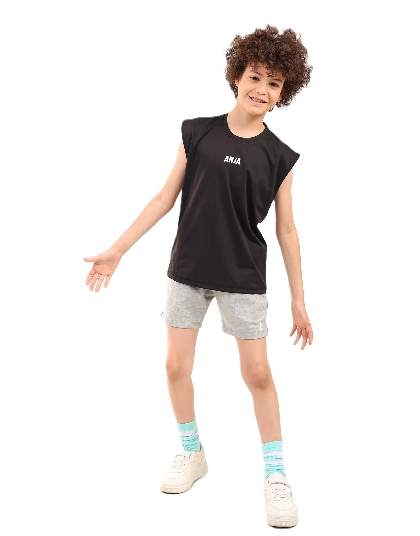 Child wearing a black sleeveless shirt with text, gray shorts, and white sneakers on a white background