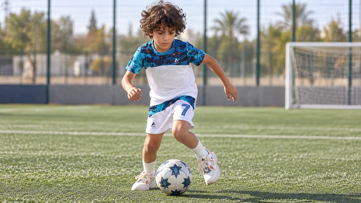 Boy dribbling a football in the ANJA blue football kit